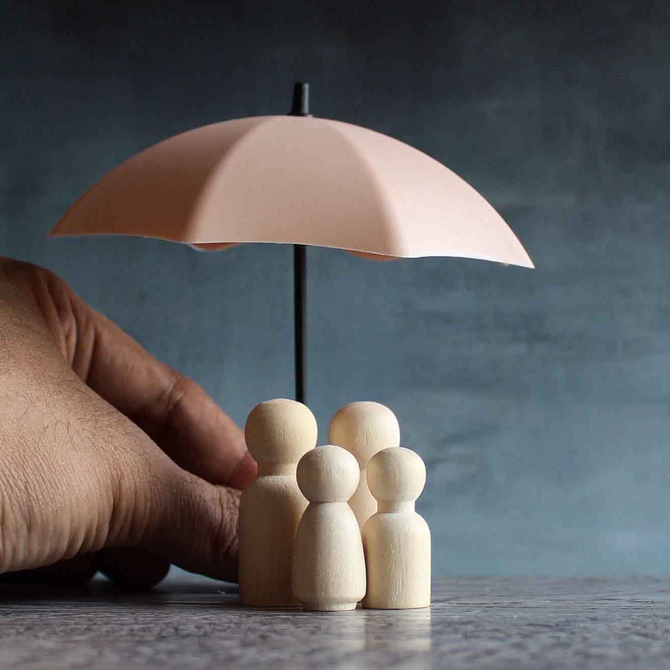 Umbrella and wooden dolls with copy space. Family protection and insurance coverage concept.